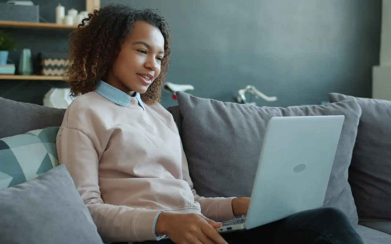 A student reviewing tuition options on a laptop at a sunny kitchen table