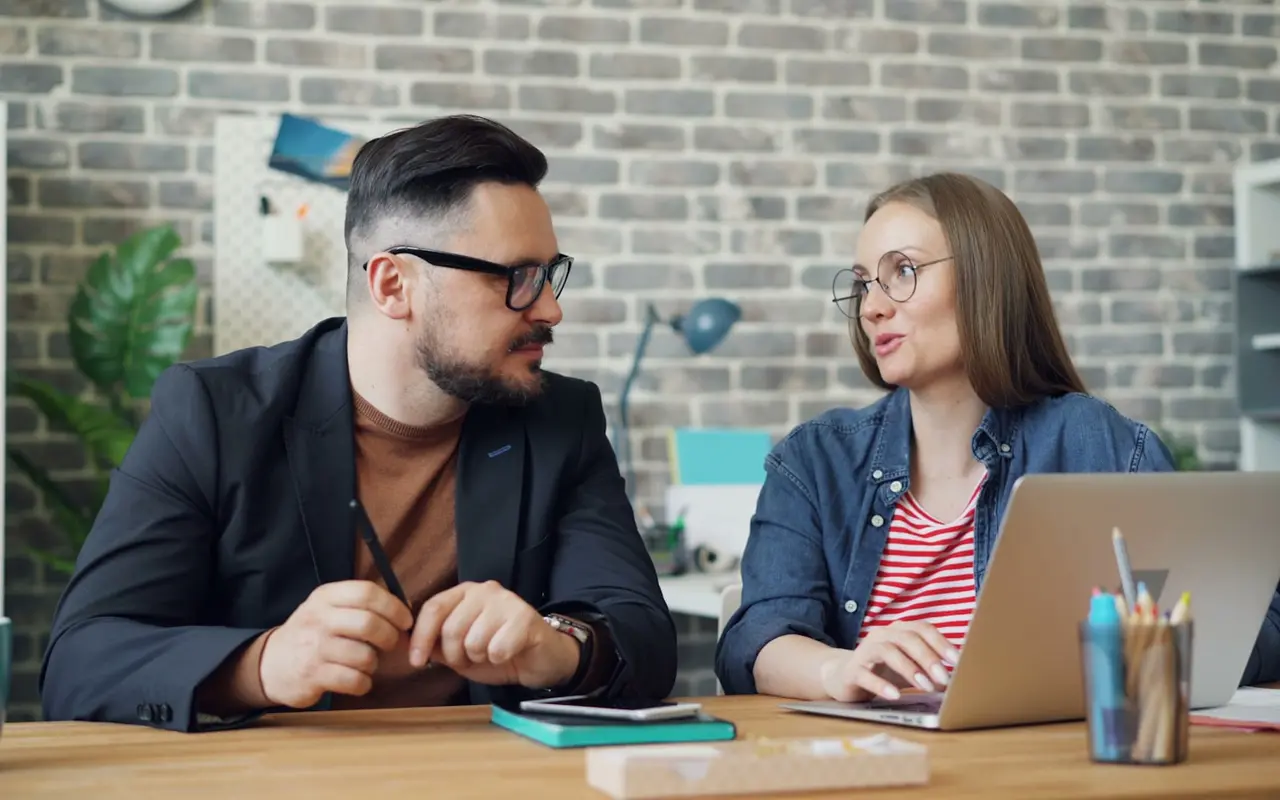 Two professionals shaking hands across a table during a partnership meeting