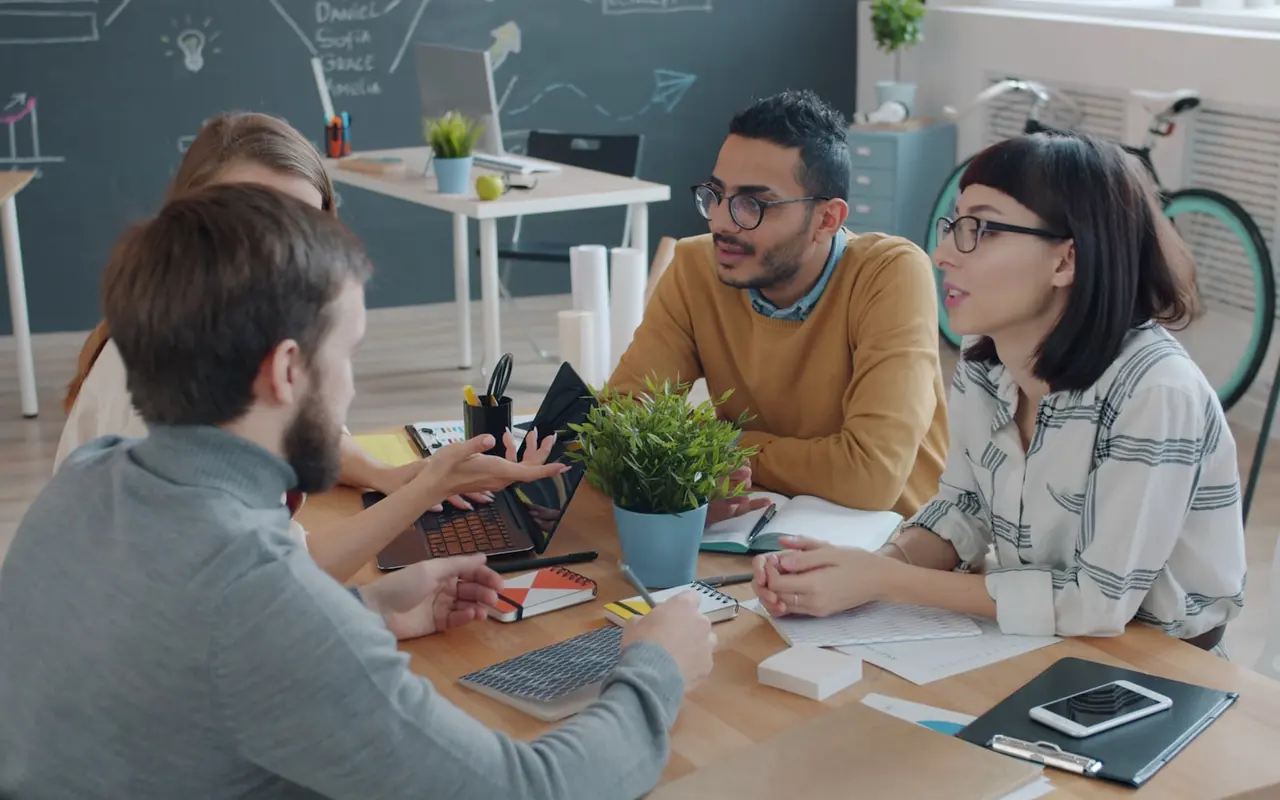 Four-person team gathered around a laptop and notebooks