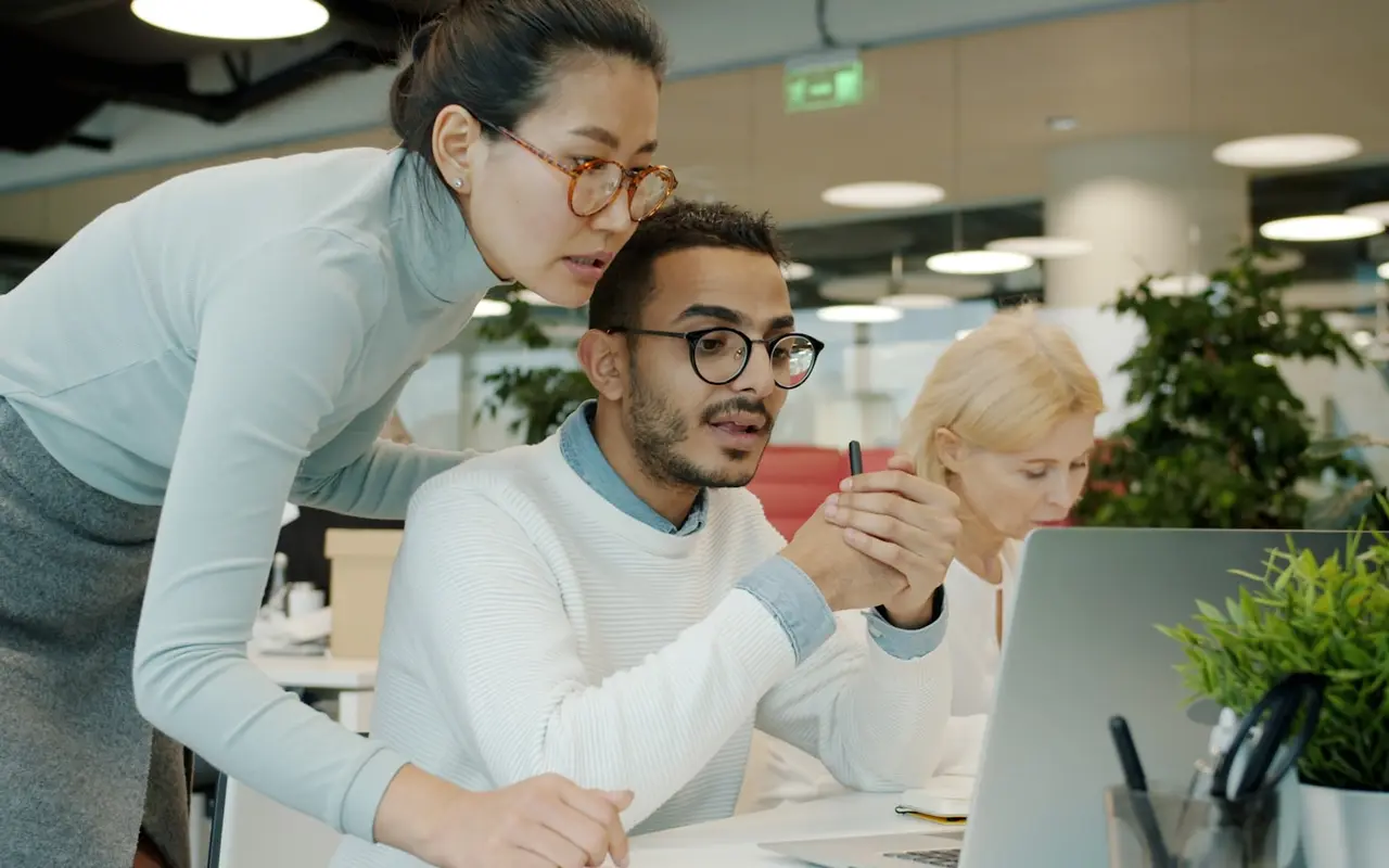 A mentor pointing something out to a seated colleague
