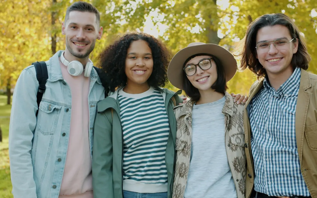 Four friends laughing together outdoors in a park