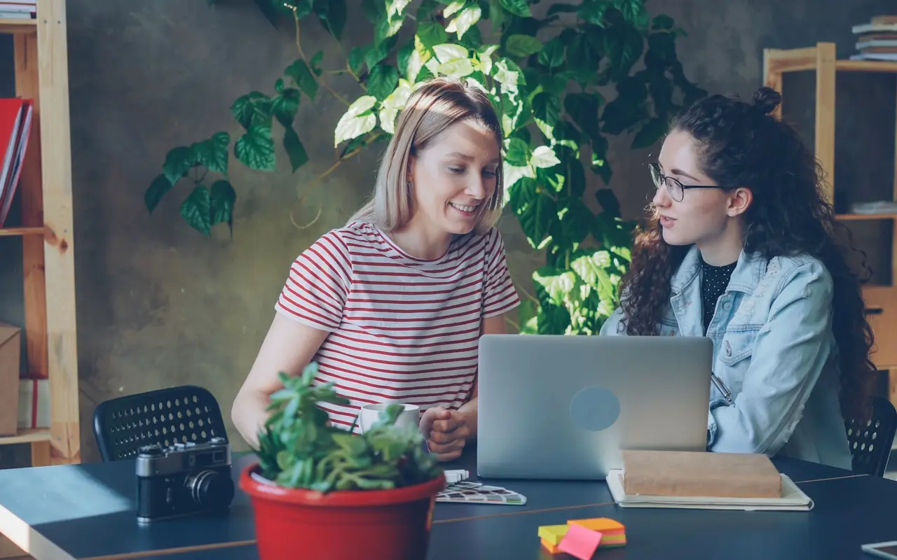 Two colleagues reviewing swatches and a camera in a plant-filled studio