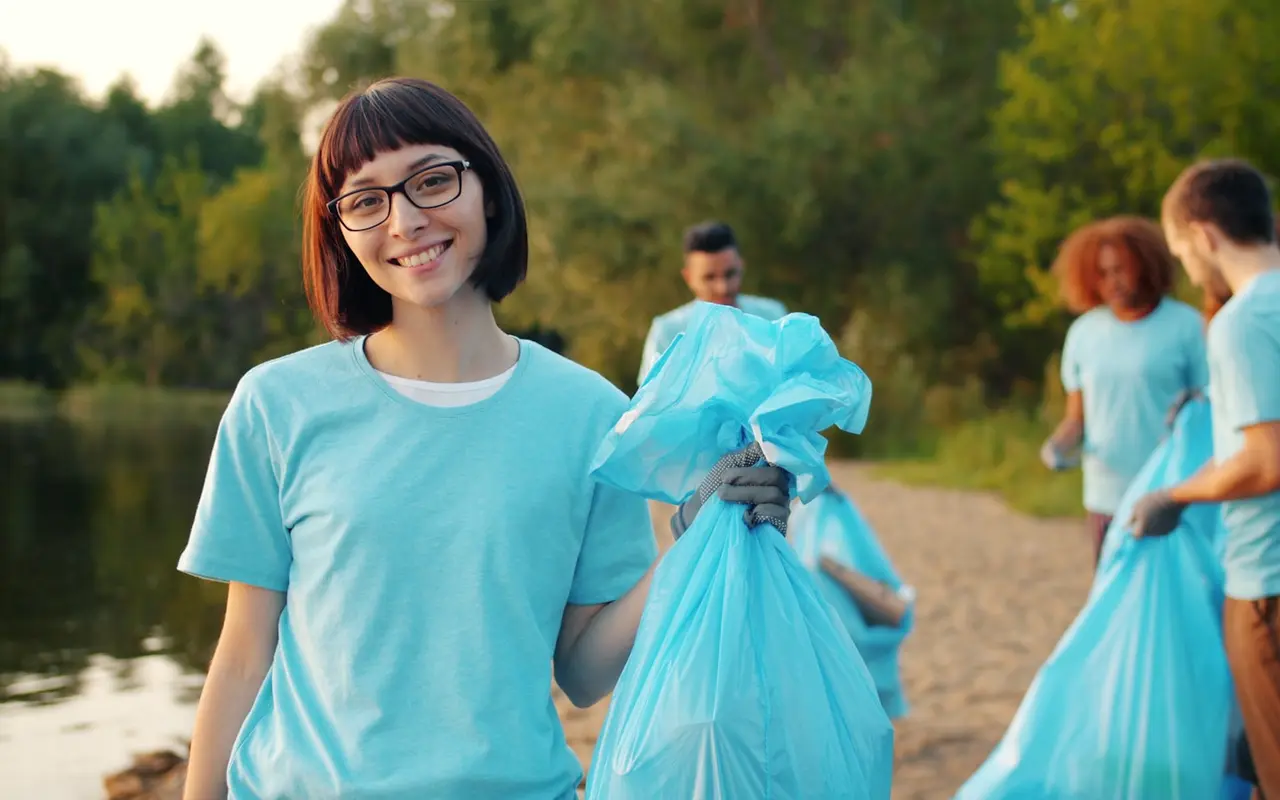 A volunteer smiling during a lakeside community cleanup